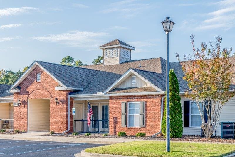 A suburban brick house with a driveway and a lamp post in the front yard.