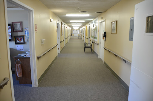 A long, empty hallway in a healthcare facility, featuring walls with light colors and overhead lighting.