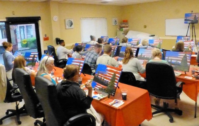 A group of people participating in a painting class, each working on their own canvas.