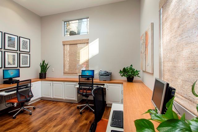 A modern home office with a spacious desk, computer setup, and natural lighting.