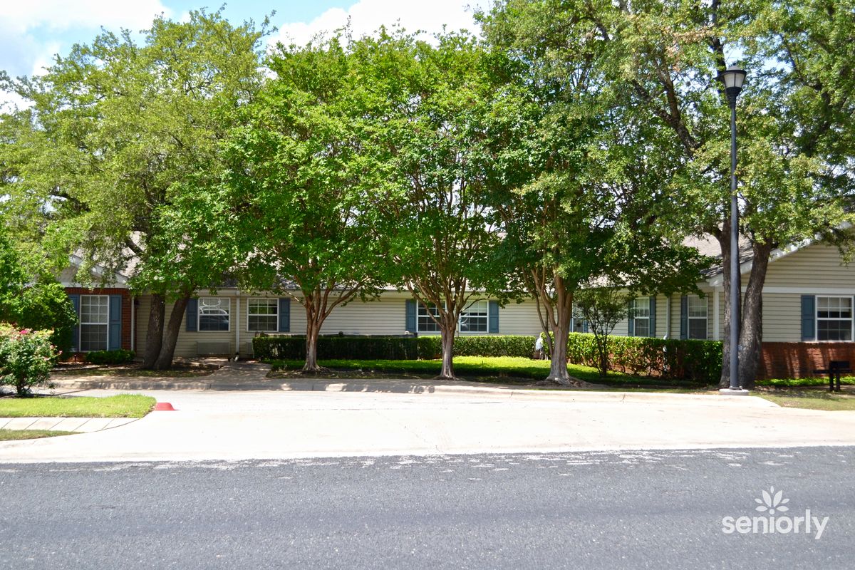 A suburban house surrounded by trees and landscaping.