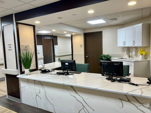A modern reception area featuring a sleek white marble countertop and green accents.