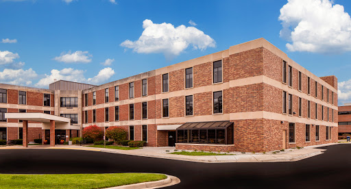 A modern brick building with large windows under a clear blue sky.