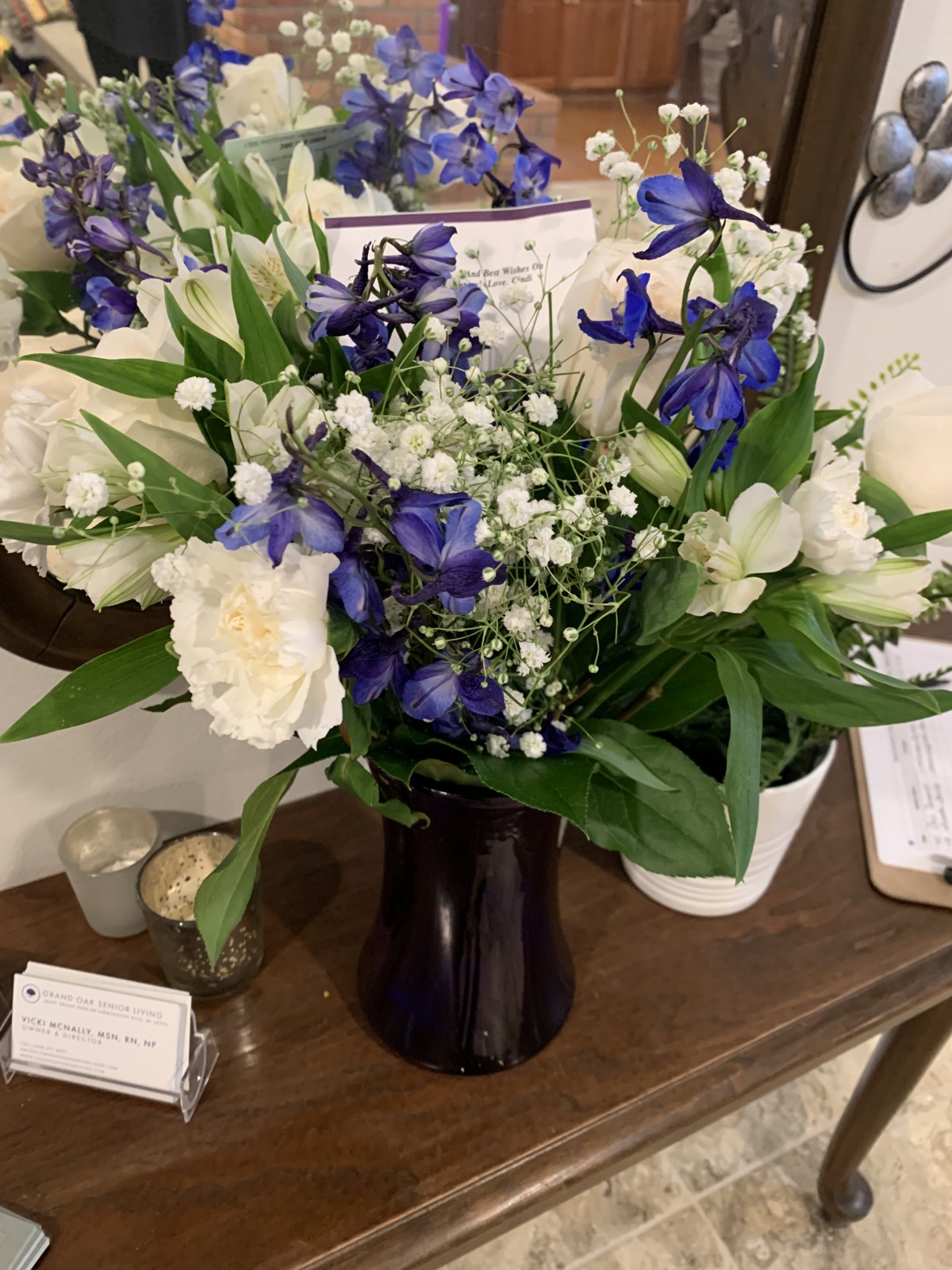 A beautiful bouquet of white and purple flowers arranged in a dark vase on a wooden surface.