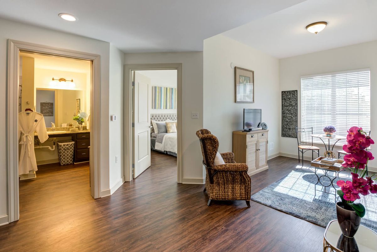 A cozy apartment interior featuring a living room with hardwood floors and a view into the bedroom.