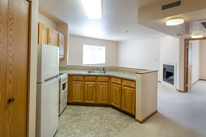 A modern apartment kitchen with wooden cabinets and standard appliances.