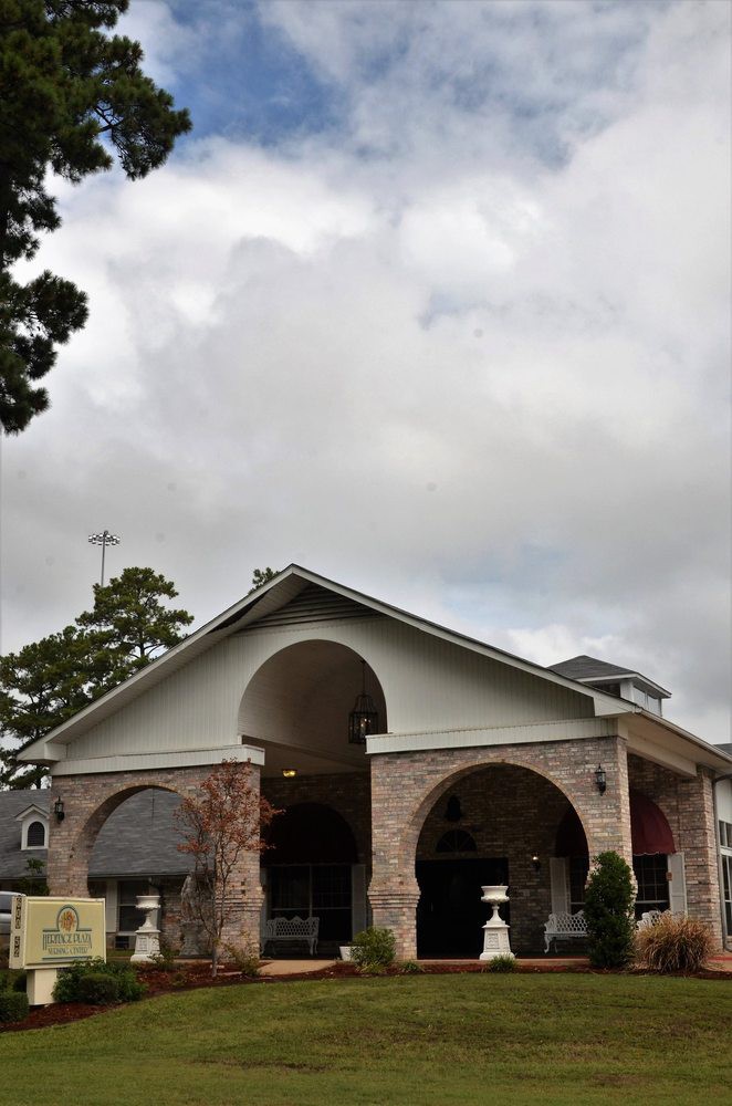 A brick building with arched entrances under a cloudy sky.