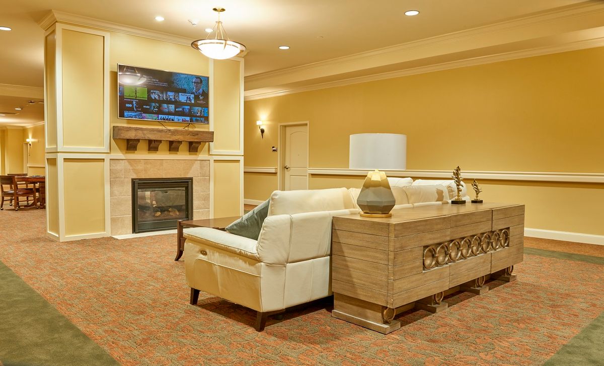 A cozy living room with modern decor, featuring a plush sofa, fireplace, and television.