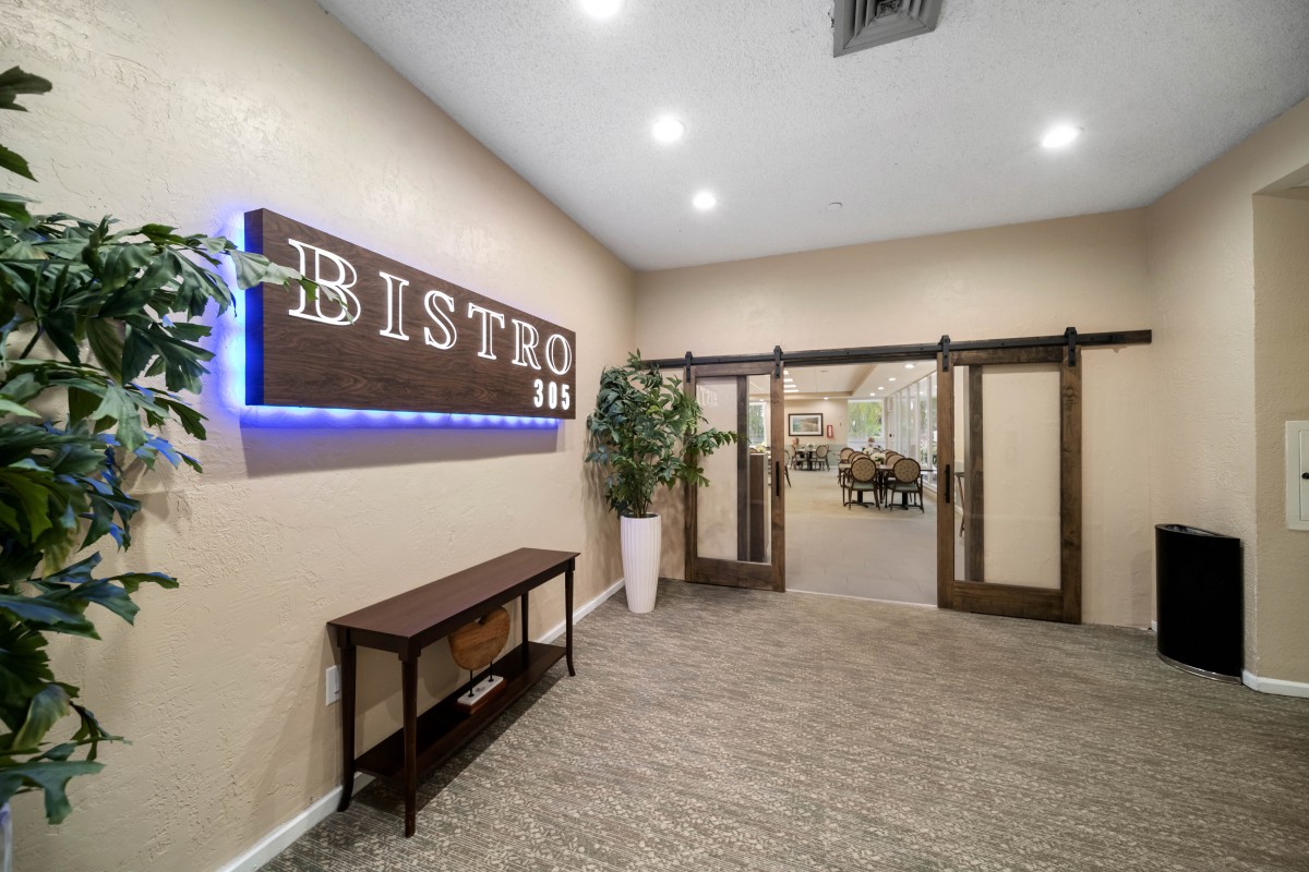 Entrance to a modern bistro with signage and decorative plants.