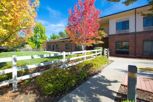 A picturesque autumn scene featuring a charming house surrounded by colorful trees and a white fence.