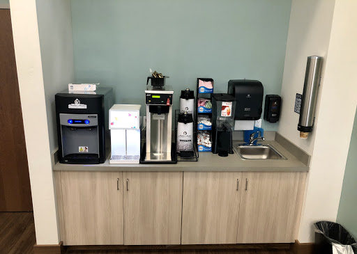 A well-equipped beverage station in an office break room featuring various coffee and water machines.