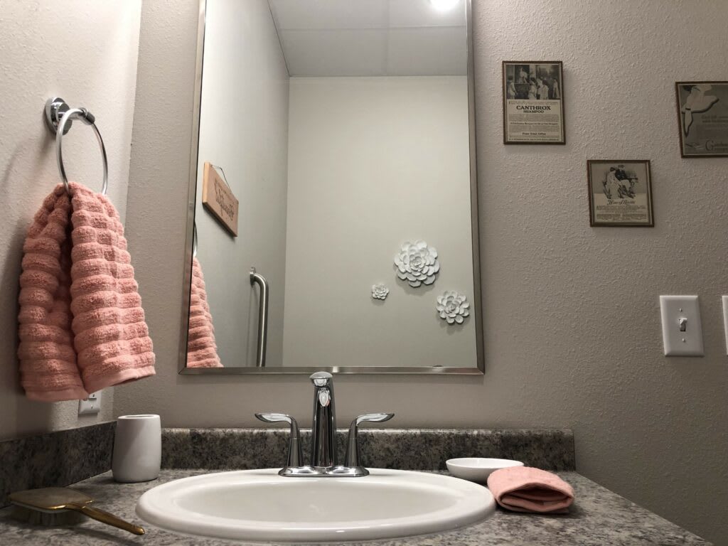 A bathroom with a sink, mirror, and neatly arranged towels.
