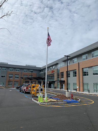 A modern building with an American flag in front, under a cloudy sky.
