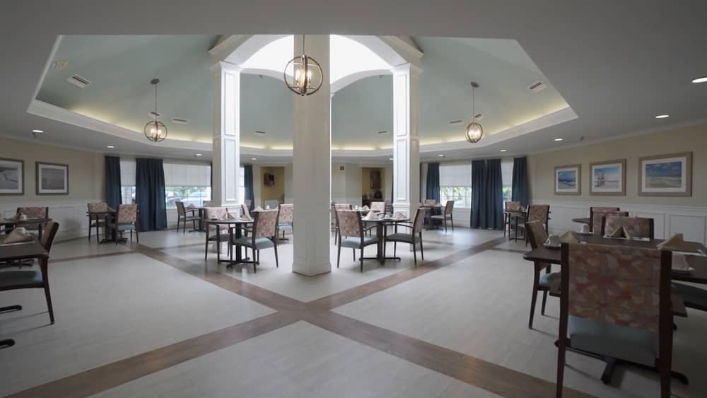 A modern and spacious dining area with elegant lighting fixtures and neatly arranged tables and chairs.
