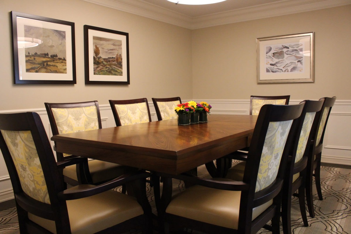 A cozy dining room with a wooden table surrounded by chairs and adorned with artwork on the walls.