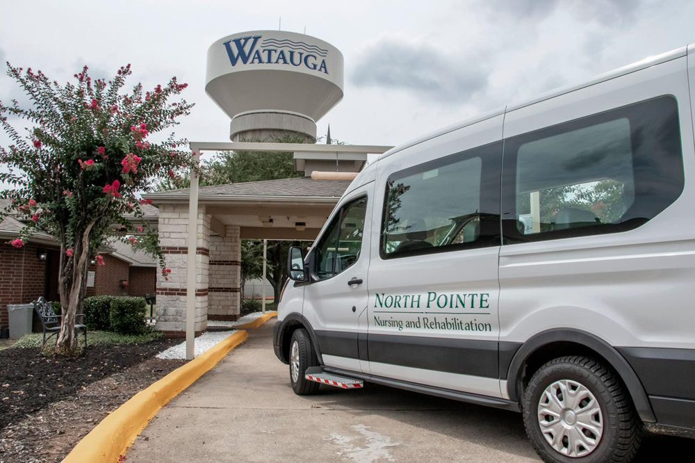 A van parked in front of a building with a water tower labeled 'Watauga' in the background.