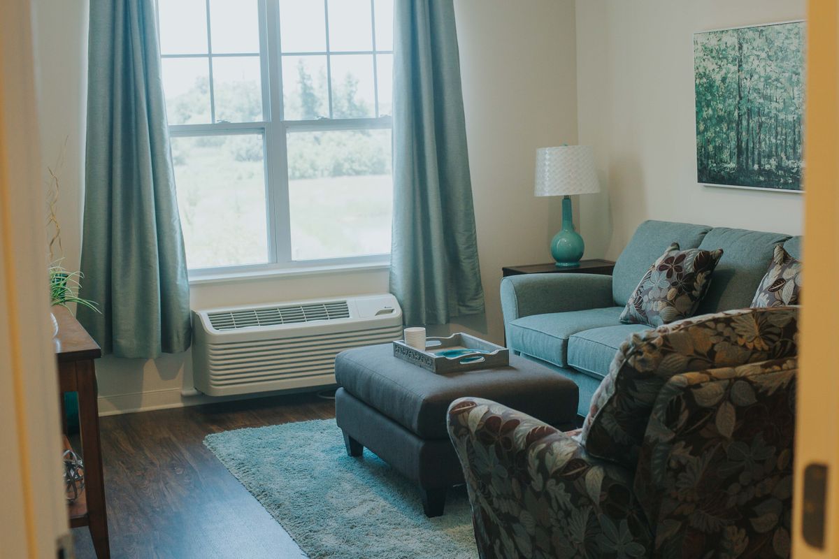 Cozy living room with a sofa, armchair, and a large window letting in natural light.