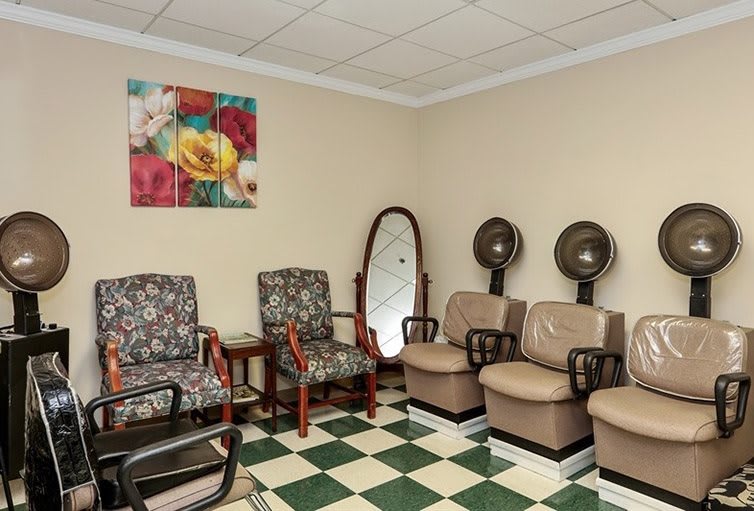 A cozy hair salon waiting area with chairs, dryers, and decorative elements.