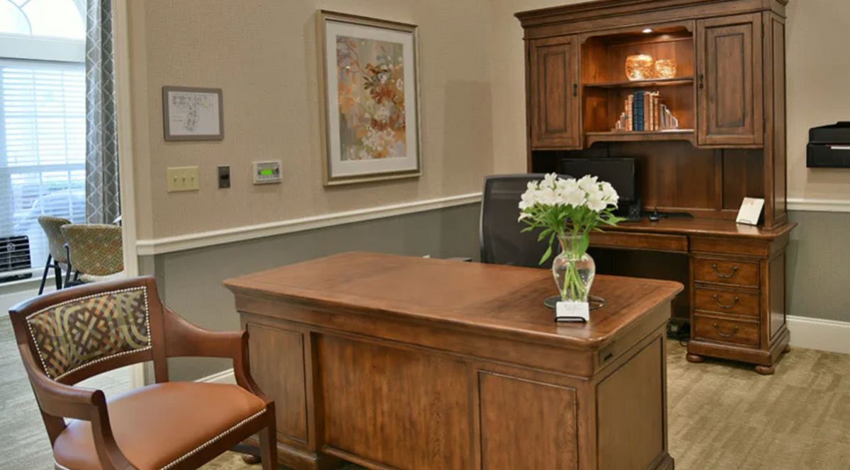A well-organized office space featuring a wooden desk and chair, with flowers as decoration.