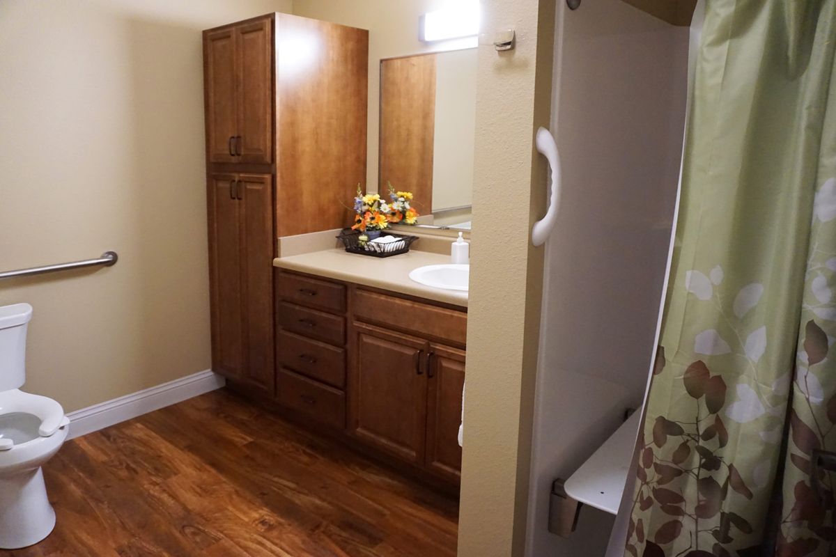A cozy bathroom with wooden cabinets, a large mirror, and a shower area.