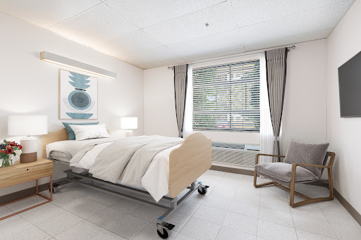 A modern hospital room featuring a comfortable bed, large window with curtains, and a chair, designed for patient care.