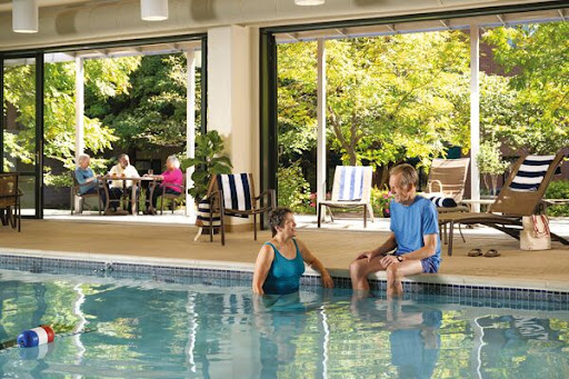 A couple enjoys a relaxing moment at an indoor pool, surrounded by greenery.
