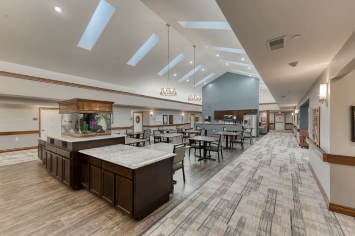 A modern dining area with skylights, featuring tables and chairs under elegant chandeliers.
