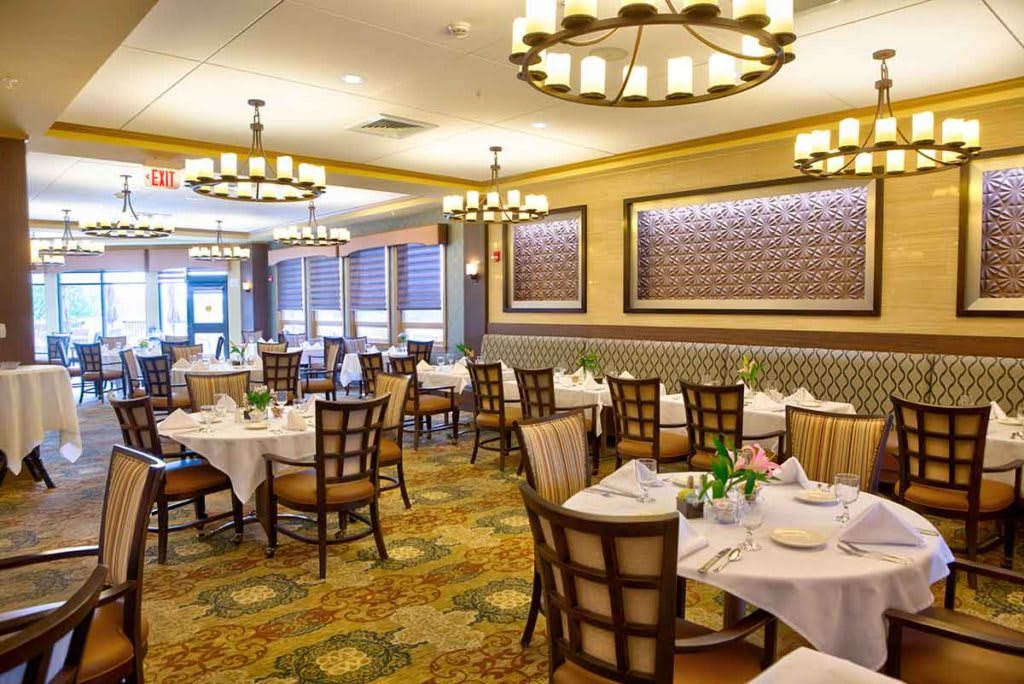 A spacious restaurant dining area with elegantly set tables and stylish lighting fixtures.