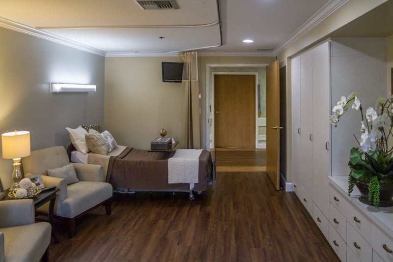 A modern hospital room with a patient bed and comfortable seating.