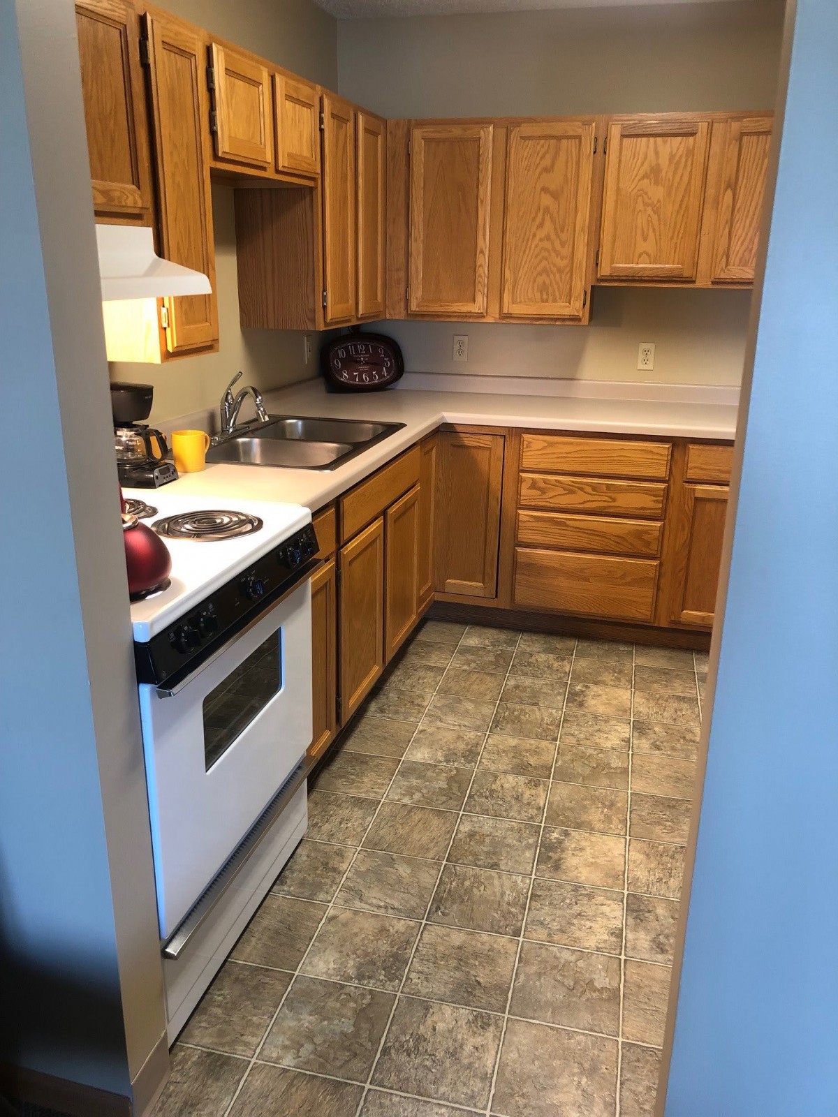 A small kitchen with wooden cabinets and a white stove.
