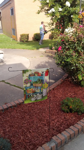 A colorful garden flag displayed in a lush outdoor setting.