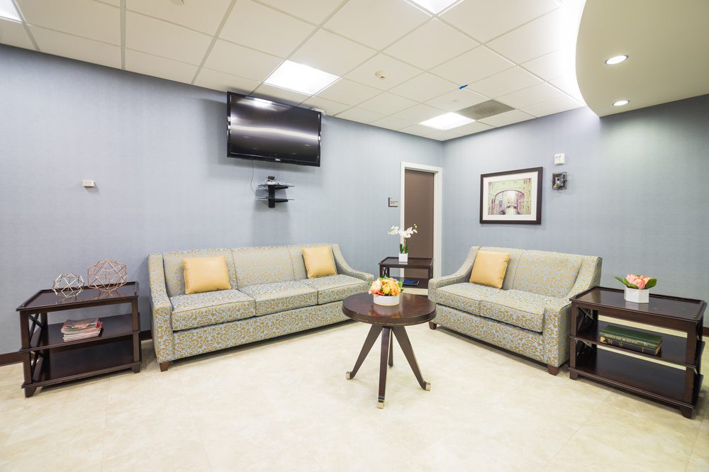 A modern waiting room with sofas and a television.