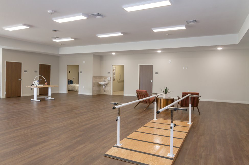 A spacious rehabilitation room equipped with parallel bars for physical therapy exercises.