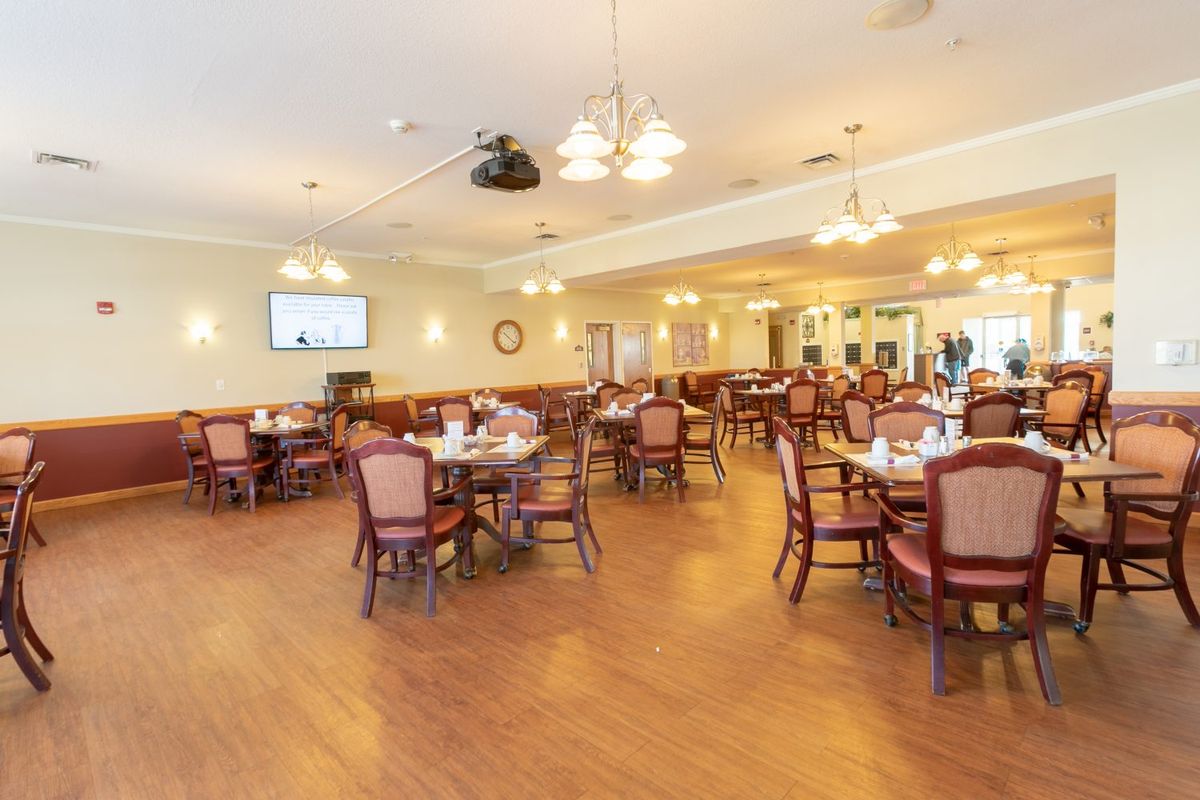 An empty dining room with neatly arranged tables and chairs, illuminated by warm lighting.