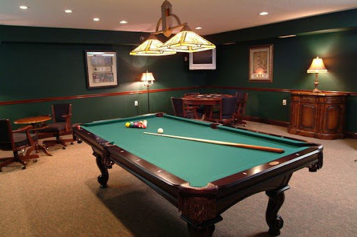 A cozy game room featuring a classic pool table with green felt and warm lighting.