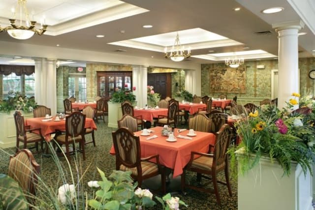 An elegant dining room with neatly arranged tables and chairs, adorned with plants and sophisticated decor.
