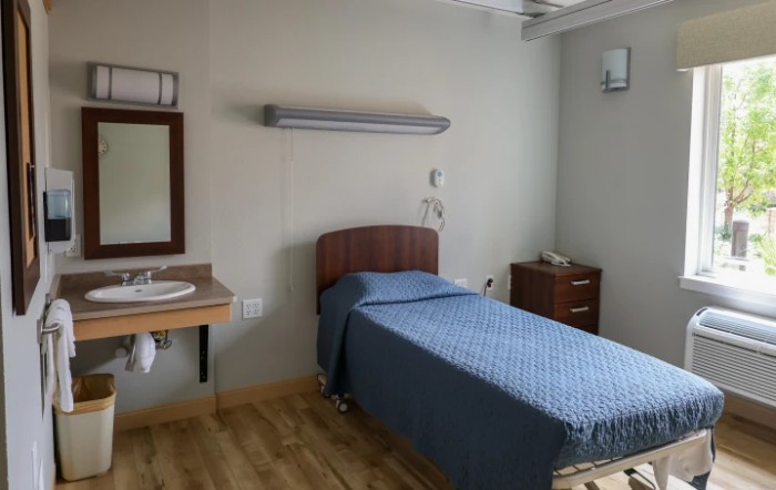A clean hospital room with a single bed and medical equipment.