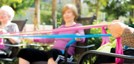 An elderly person exercising with resistance bands outdoors.