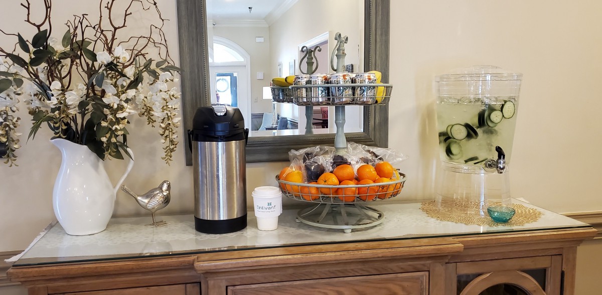 A refreshment station with coffee, snacks, and fresh oranges on a countertop.