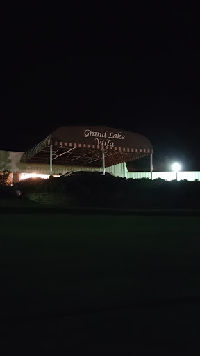 A nighttime view of a building with a canopy, featuring the name 'Grand Lake Inn' illuminated.