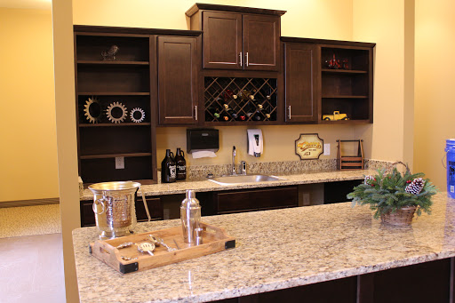 A stylish modern kitchen featuring dark cabinetry and a granite countertop, complete with wine storage.