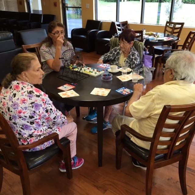 A group of elderly people sitting around a table socializing indoors.