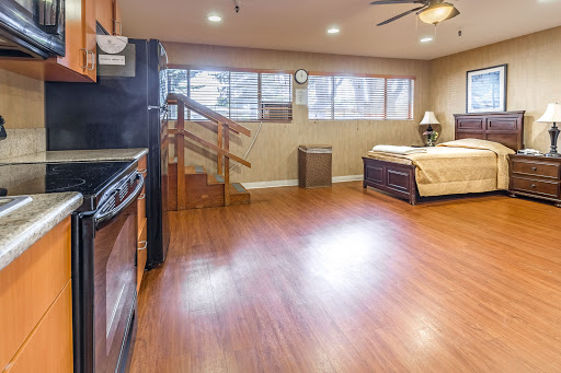 A spacious studio apartment featuring a kitchenette, wooden flooring, and ample natural light.