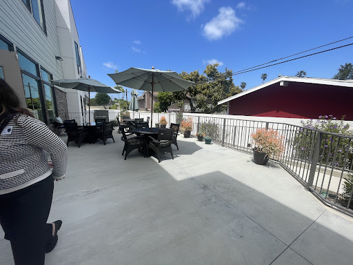 A spacious outdoor patio area with black furniture and umbrellas, perfect for enjoying a sunny day.