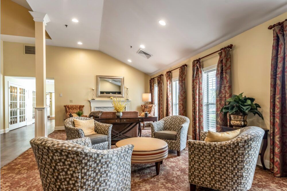 A cozy living room featuring patterned chairs and a round table, with warm lighting and elegant curtains.