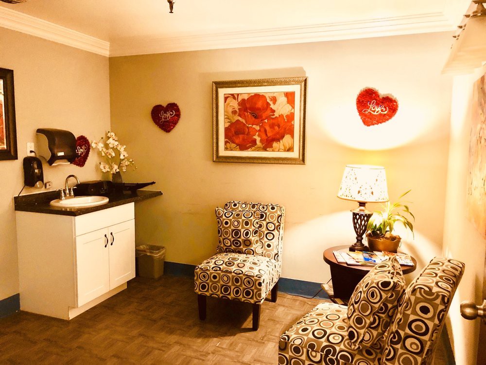 A cozy waiting room with patterned chairs, heart decorations, and a warm lamp.