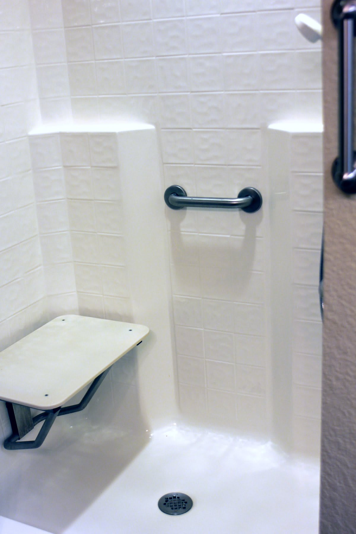 An accessible shower with a grab bar and folding seat for enhanced safety.