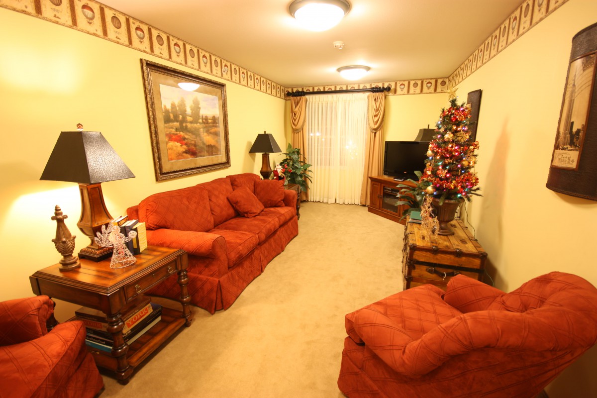 A cozy living room featuring a red sofa set and festive decorations, including a Christmas tree.