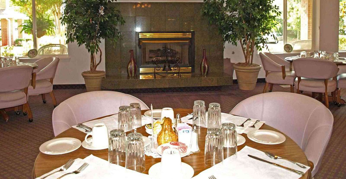 A dining table set with glasses and plates in a cozy restaurant with a fireplace.