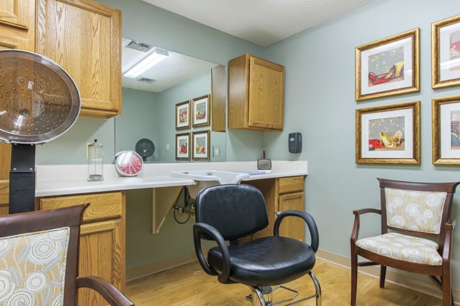 A hair salon interior with a styling chair, mirror, and wooden cabinets.